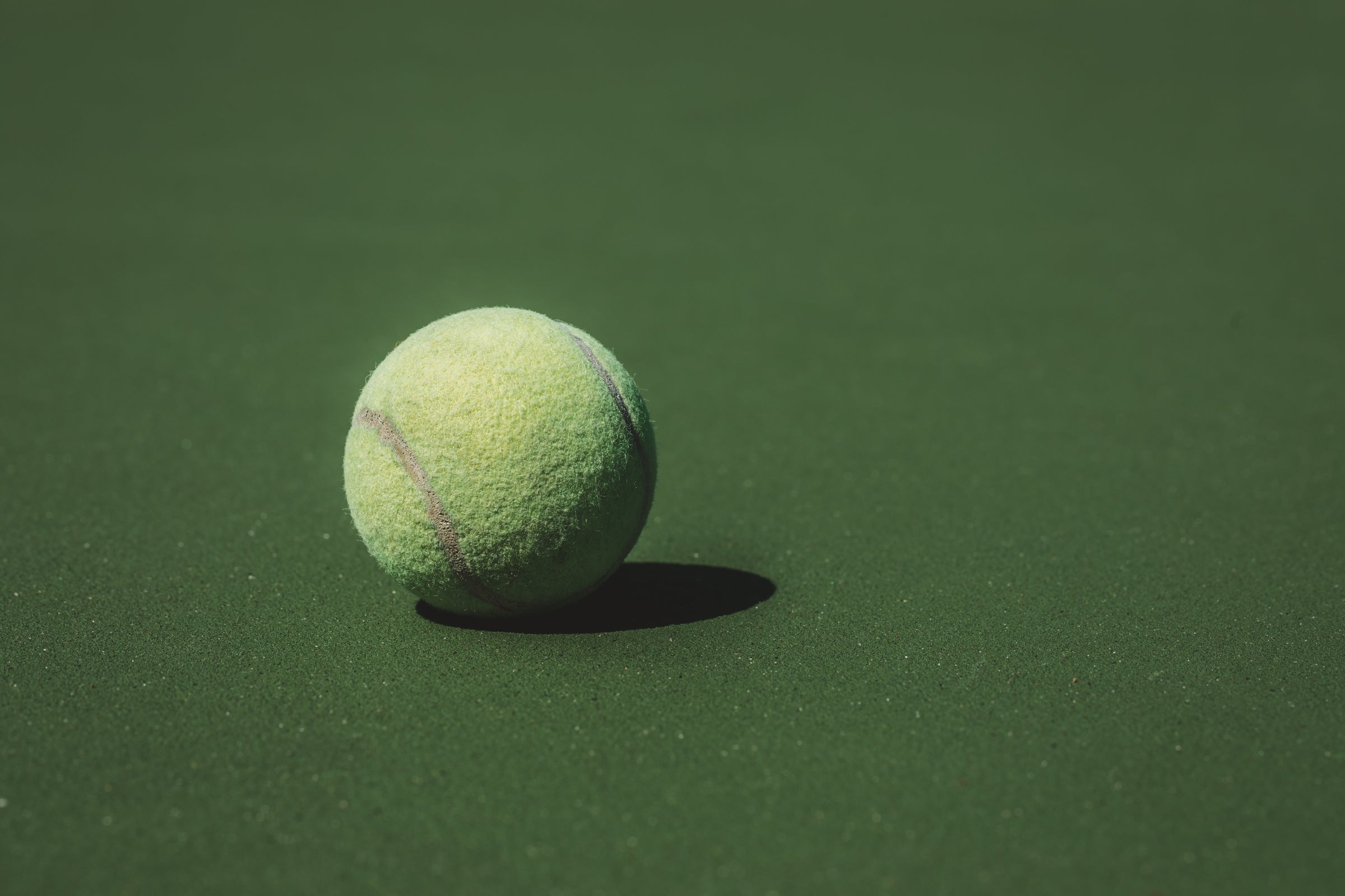 Auf einem Rasenplatz liegt ein Tennisball in der Sonne. In dieser Situation bist du mit unseren 720°DGREE Trinkflaschen perfekt ausgestattet.
